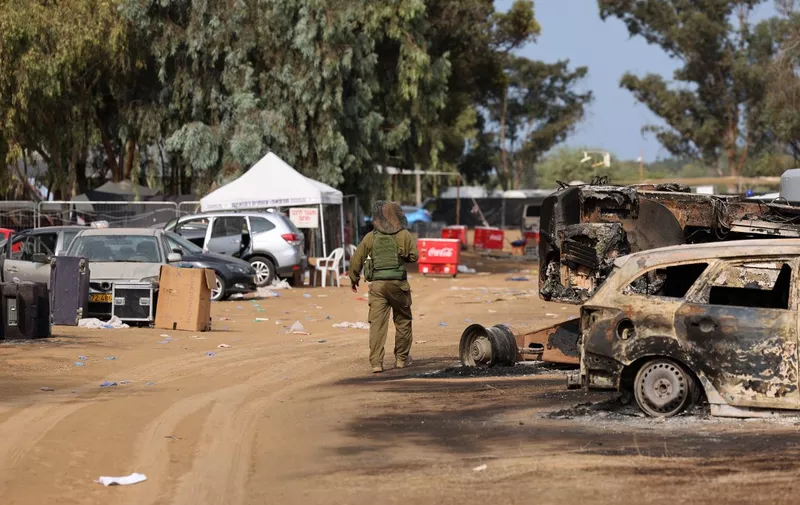 An Israeli soldier walks past burnt vehicles at the site of the weekend attack on the Supernova desert music Festival by Palestinian militants near Kibbutz Reim in the Negev desert in southern Israel on October 10, 2023. Hamas gunmen killed around 270 revellers who were attending an outdoor rave music festival in an Israeli community near Gaza at the weekend, a volunteer who helped collect the bodies said on October 9. (Photo by JACK GUEZ / AFP)
