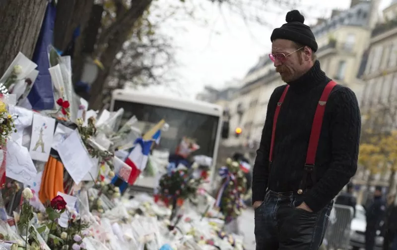 Singer of the US rock group Eagles of Death metal Jesse Hughes pays tribute to the victims of the November 13 Paris terrorist attacks at a makeshift memorial in front of the Bataclan concert hall on December 8, 2015 in Paris. 
The Eagles of Death Metal band returned to the Bataclan concert hall in Paris, nearly a month after they survived a jihadist attack there in which 90 people died. / AFP / MIGUEL MEDINA