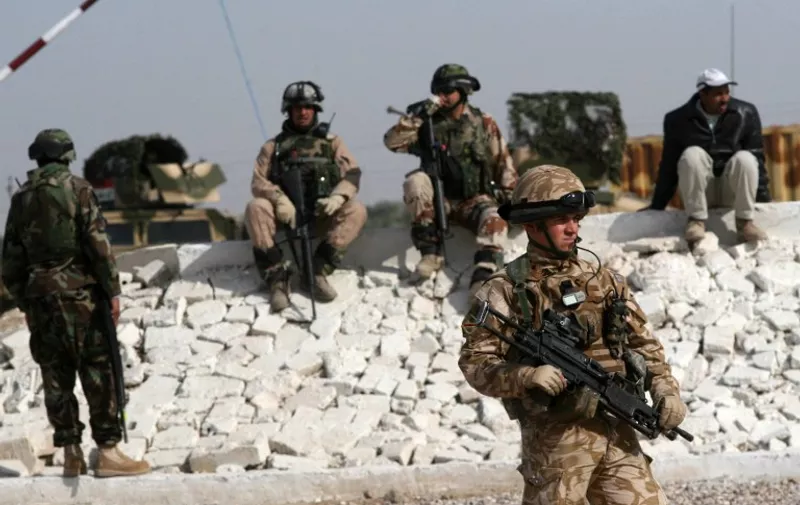 Iraqi soldiers (back) and a British soldier (front) watch during an Iraqi army training session run with the advice and support of the British at a location in the north of the southern Basra province on December 18, 2008.  Britain will withdraw all but 400 of its troops from Iraq by the end of next July, Prime Minister Gordon Brown said today, but rejected any link with pressure to send more forces to Afghanistan. AFP PHOTO/ESSAM AL-SUDANI / AFP / ESSAM AL-SUDANI