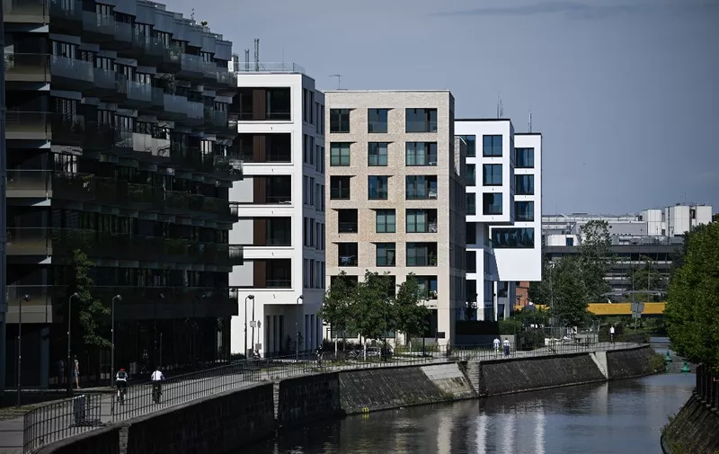 People walk past apartment buildings on the banks of the river Spree in the Heidestrasse quarter in Berlins Mitte (Centre) district in the German capital, on August 14, 2023. Since 2018, the Heidestrasse area of some 85.000 square meters has been constructed with new buildings for housing, working, shopping. (Photo by Tobias SCHWARZ / AFP)