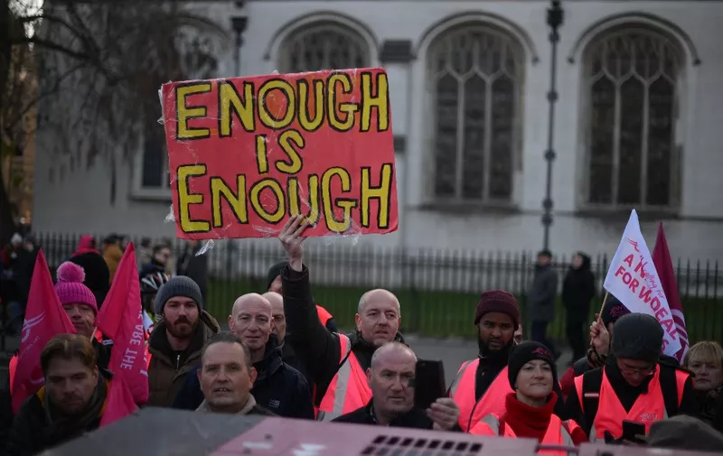 A demonstrator holds a sign reading 'Enough is Enough' as they take part in a rally organised by the Communication Workers Union (CWU), in support of Royal Mail postal workers who are on strike, in Parliament Square in central London on December 9, 2022. - The Communication Workers Union said postal workers had voted overwhelmingly for more strikes this year and next, affecting deliveries in the run-up to Christmas and opening hours at post offices. Formerly state-owned Royal Mail recently announced it would axe up to 10,000 jobs, blaming the move partly on staff strikes that contributed to a first-half loss. (Photo by Daniel LEAL / AFP)