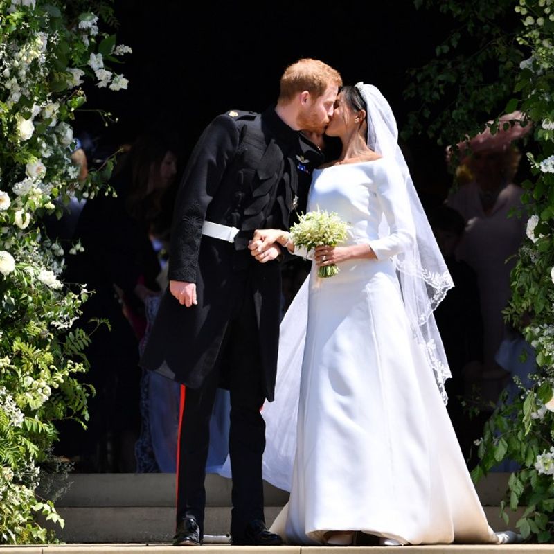 Britain's Prince Harry, Duke of Sussex kisses his wife Meghan, Duchess of Sussex as they leave from the West Door of St George's Chapel, Windsor Castle, in Windsor, on May 19, 2018 after their wedding ceremony. (Photo by Ben STANSALL / POOL / AFP)