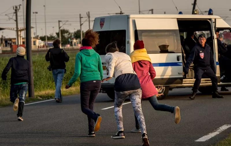 Migrants who managed to get past roadblocks set up by French gendarmes inside the Eurotunnel site run to the boarding platform to attempt to reach Britain, in Coquelles near Calais, northern France, on July 31, 2015. The situation appears to have calmed in the past two days, after migrants made more than 2,000 daily attempts to breach the defences earlier in the week. The crisis has strained relations between Paris and London and the British government was poised to hold emergency talks later on July 31 on the issue. AFP PHOTO / PHILIPPE HUGUEN