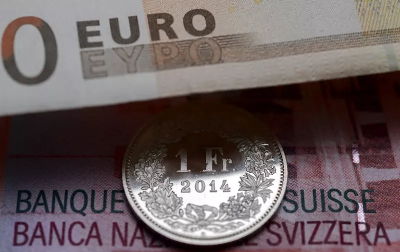 A Swiss coin is seen beneath a euro banknote on Januay 15, 2015 in Lausanne. In a shock announcement on January 15, Switzerland's central bank said it was ending a three-year bid to artificially hold down the value of the Swiss franc against the euro, in a move that immediately sent the safe haven currency soaring. AFP PHOTO / FABRICE COFFRINI / AFP / FABRICE COFFRINI