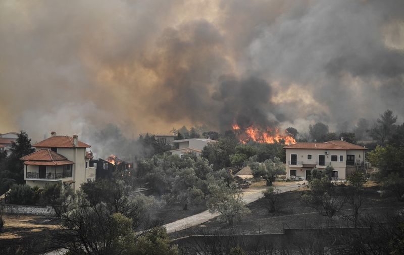 A picture taken on August 6, 2021 shows flames near houses as a fire spreads in the village of Afidnes, some 30 kilometres north of Athens. - Hundreds of firefighters battled a blaze on the outskirts of Athens on August 6 as dozens of fires raged in Greece. (Photo by LOUISA GOULIAMAKI / AFP)