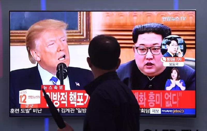 A man walks past a television news screen showing North Korean leader Kim Jong Un (R) and US President Donald Trump (L) at a railway station in Seoul on May 16, 2018.
North Korea threatened on May 16, to cancel the forthcoming summit between leader Kim Jong Un and President Donald Trump if Washington seeks to push Pyongyang into unilaterally giving up its nuclear arsenal. / AFP PHOTO / Jung Yeon-je