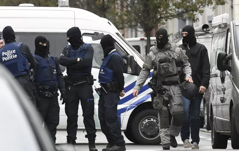 Security forces personnel walk past during ongoing operations in the Molenbeek district of Brussels on November 16, 2015. Belgian police launched a major new operation in the Brussels district of Molenbeek, where several suspects in the Paris attacks had previously lived, AFP journalists said. Armed police stood in front of a police van blocking a street in the run-down area of the capital while Belgian media said officers had surrounded a house. Belgian prosecutors had no immediate comment. AFP PHOTO / JOHN THYS / AFP / JOHN THYS