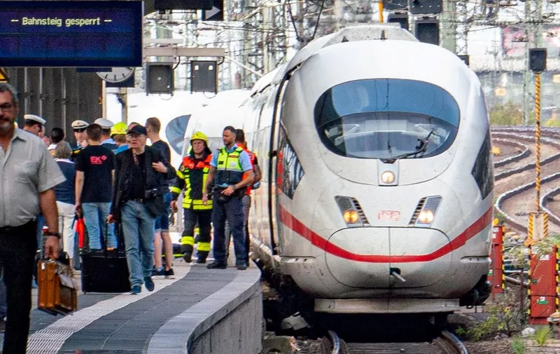 Police and medical helpers stand next to an ICE speed train at Frankfurt's main station on July 29, 2019, after a man pushed a child in front of the moving train. - The eight-year-old boy died after he was pushed along with his mother in front of the train by a 40-year-old man, police said. The suspect, who was allegedly unrelated to the victims, ran off but was overpowered by passers-by and detained by police. The woman was being treated in hospital after narrowly escaping from the tracks where an arriving ICE speed train ran over her child. (Photo by Frank Rumpenhorst / dpa / AFP) / Germany OUT
