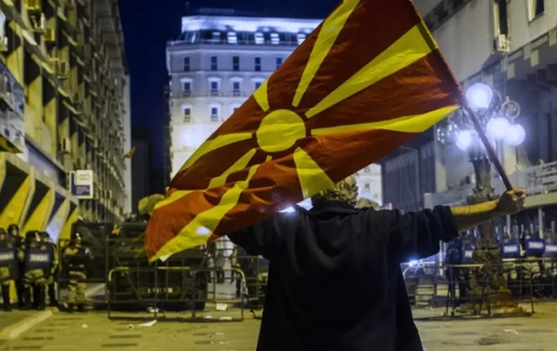 A protestor waves a Macedonian flag in front of anti-riot police in Skopje on April 14, 2016, during a protest against the president's shock decision to halt probes into more than 50 public figures embroiled in a wire-tapping scandal. 
Thousands took to the streets of the Macedonian capital for a third consecutive evening on April 14, 2016. Similar anti-government protests in the capital had turned violent on Wednesday, when demonstrators ransacked the offices used by President Gjorge Ivanov's team and set fire to the furniture.  / AFP PHOTO / Robert ATANASOVSKI