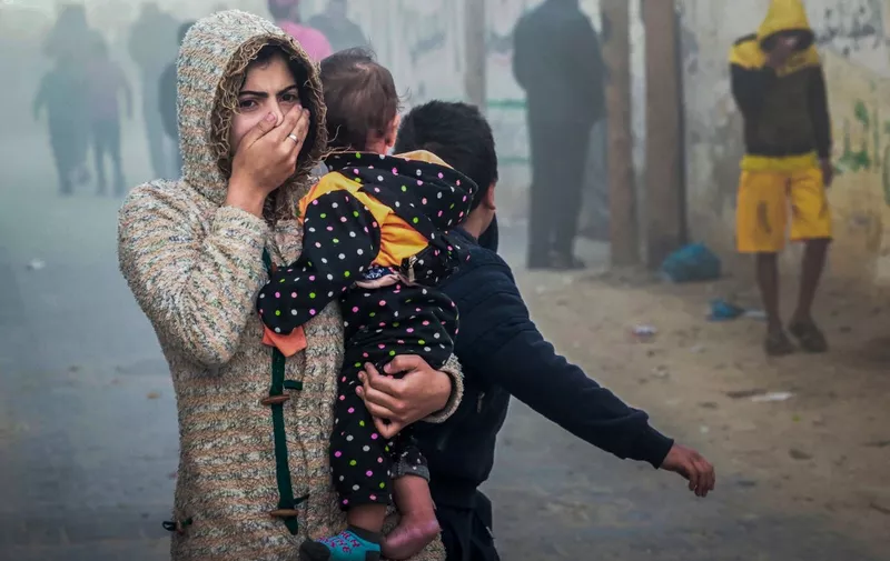 A woman holding a child flees following an Israeli strike in Rafah in the southern Gaza Strip on November 23, 2023, amid ongoing battles between Israel and the Palestinian militant group Hamas. (Photo by Mohammed ABED / AFP)