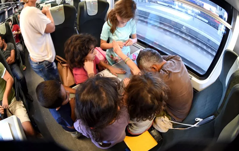 Migrants travel on a train from Budapest shortly before arrival at  Vienna's Westbahnhof railway station on August 31, 2015. Up to 300 migrants have arrived from Budapest to Vienna, Austria. Austrian security forces stopped two trains with several hundred migrants near the border with Hungary on Monday, a police spokesman said, hours after authorities in Budapest let them leave despite many not having EU visas.  AFP PHOTO / JOE KLAMAR