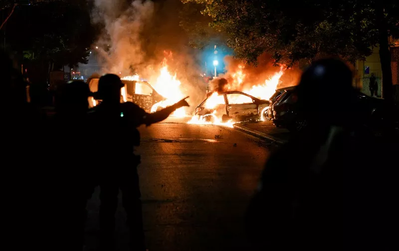Police officers stand near burning cars during protests in Nanterre, west of Paris, on June 28, 2023, a day after the killing of a 17-year-old boy in Nanterre by a police officer's gunshot following a refusal to comply. (Photo by Geoffroy Van der Hasselt / AFP)