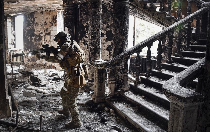 A Russian soldier patrols at the Mariupol drama theatre, bombed last March 16, on April 12, 2022 in Mariupol, as Russian troops intensify a campaign to take the strategic port city, part of an anticipated massive onslaught across eastern Ukraine, while Russia's President makes a defiant case for the war on Russia's neighbour. - *EDITOR'S NOTE: This picture was taken during a trip organized by the Russian military.* (Photo by Alexander NEMENOV / AFP)