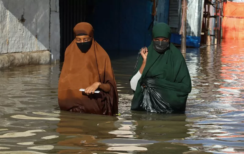 Women walk through floodwater in Beledweyne, central Somalia, on May 12, 2023. The Shabelle River has burst its banks in Beledweyne, in central Somalia, forcing thousands of people to abandon their homes, according to the United Nations Office for the Coordination of Humanitarian Affairs (OCHA), and submerging markets and hospitals. (Photo by Hassan Ali ELMI / AFP)