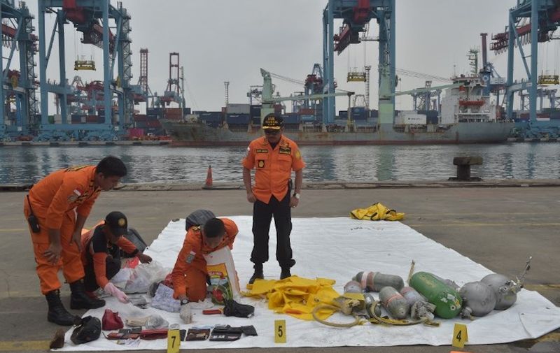 Indonesian SAR members display personal items of passengers of the ill-fated Lion Air flight JT 610 at the Jakarta port on October 30, 2018. - Indonesian search teams recovered more remains at the site of a crashed Lion Air jet that plunged into the sea with 189 people aboard, as a report said it had suffered an instrument malfunction the day before. (Photo by ADEK BERRY / AFP)