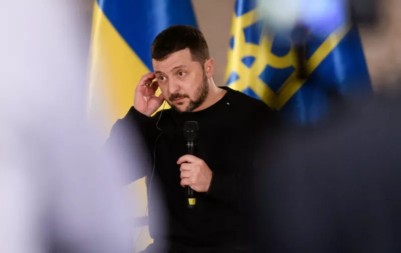 Ukraine's President Volodymyr Zelensky touches his earpiece during a questions and answers session with International media representatives in the Latvian National History Museum on January 11, 2024 in Riga, Latvia. (Photo by Gints Ivuskans / AFP)