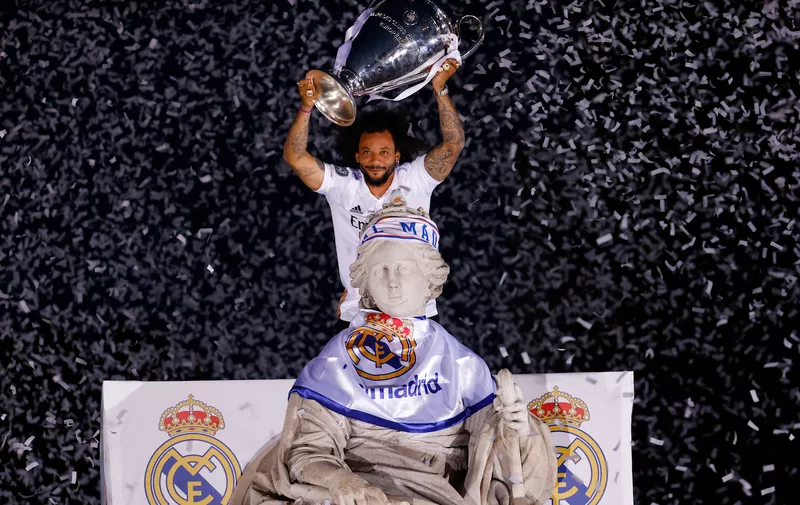 Soccer Football - Real Madrid celebrate winning the Champions League Final with an open top bus parade - Madrid, Spain - May 29, 2022 
Real Madrid's Marcelo lifts the Champions League trophy on top of a statue during the victory parade REUTERS/Marcelo Del Pozo