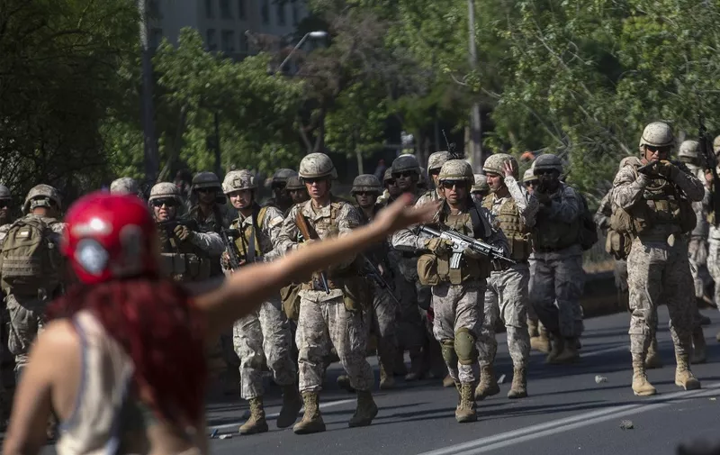 Chilean soldiers walk towards demonstrators during protests in Santiago, on October 20, 2019. - Fresh clashes broke out in Chile's capital Santiago on Sunday after two people died when a supermarket was torched overnight as violent protests sparked by anger over economic conditions and social inequality raged into a third day. (Photo by CLAUDIO REYES / AFP)