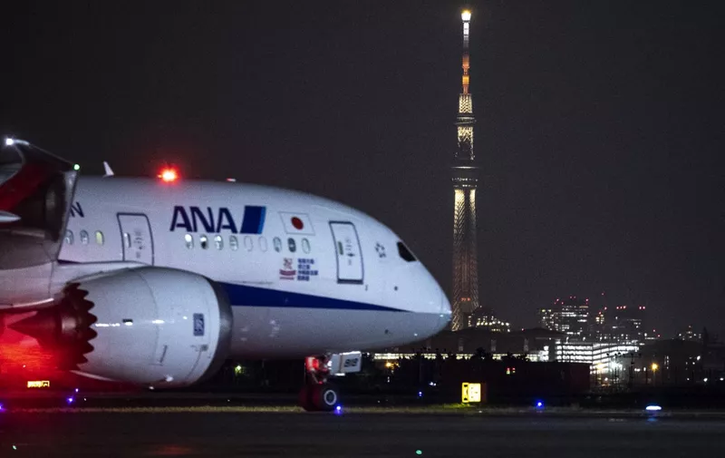 This picture shows the Tokyo Skytree, Japan's tallest structure at 634 meters (2,080 feet) and an All Nippon Airways (ANA) aircraft on the tarmac of Tokyo's Haneda airport on May 23, 2022. (Photo by Charly TRIBALLEAU / AFP)