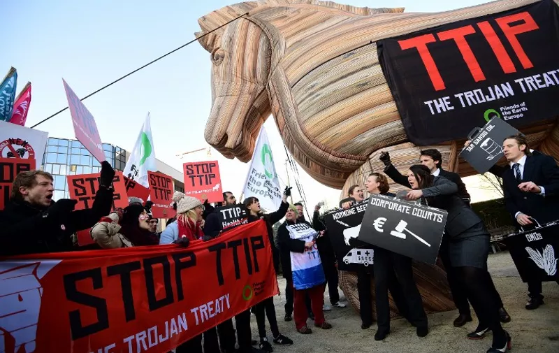 Demonstrators from grassroots environmental network Friends of the Earth Europe (FoEE) stage a protest against the Transatlantic Trade and Investment Pact (TTIP) in front of the the European institutions in Brussels, on February 4, 2015.  US and EU negotiators began their latest round of talks on February 2 seeking to push through the world's biggest-ever free trade deal, which after nearly two years remain bogged down by public opposition. AFP PHOTO / EMMANUEL DUNAND