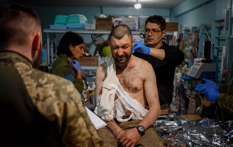 Military medics give first aid to a wounded Ukrainian serviceman at a frontline medical stabilisation point near the frontline city of Bakhmut, Donetsk region, on May 4, 2023, amid the Russian invasion of Ukraine. (Photo by Dimitar DILKOFF / AFP)