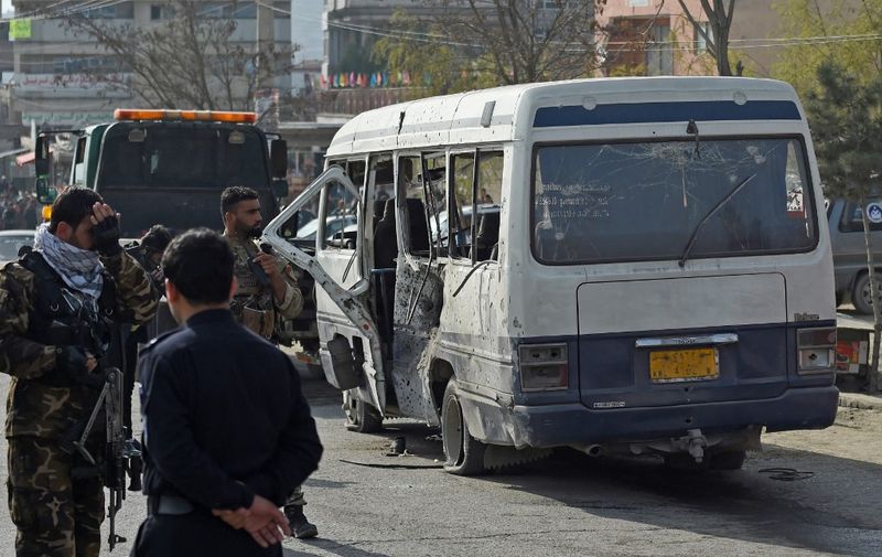 Security personnel are seen near a damaged vehicle after a blast in Kabul on March 18, 2021. (Photo by WAKIL KOHSAR / AFP)