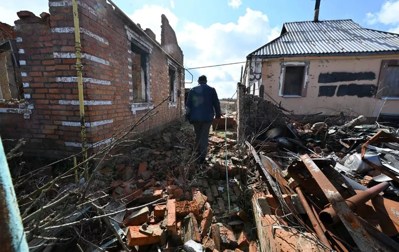 A local resident walks past destroyed houses in the village of Russkiye Tishki in the north of Kharkiv region on March 27, 2023. (Photo by SERGEY BOBOK / AFP)