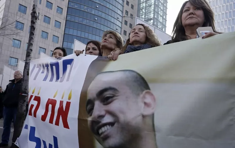 Israeli women protest outside the defence ministry in Tel Aviv on January 4, 2017, in support of Israeli soldier Elor Azaria (portrait), who shot dead a wounded Palestinian assailant, as they wait for his verdict in a case that deeply divided the country and set off political tensions.
The soldier, Elor Azaria, has been on trial for manslaughter in a military court since May, with right-wing politicians defending him despite top army brass harshly condemning the killing.

 / AFP PHOTO / Jack GUEZ