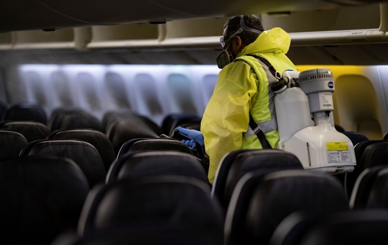 A member of Charles de Gaulle airport personnel nebulizes the interior of an Air France aircraft as part of a disinfection process for airplane, in Terminal 2 of Charles de Gaulle international airport in Roissy near Paris, on May 14, 2020, as France eases lockdown measures taken to curb the spread of the COVID-19 (the novel coronavirus). (Photo by Ian LANGSDON / EPA POOL / AFP)