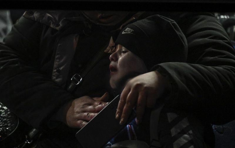 A woman comforts a child as they sit on a shuttle bus transporting refugees to the nearby town, after crossing the Ukrainian border with Poland at the Medyka border crossing, southeastern Poland, on March 11, 2022. - More than two and a half million people have fled the "senseless war" in Ukraine, the UN said on March 11 -- more than half to Poland. (Photo by Louisa GOULIAMAKI / AFP)