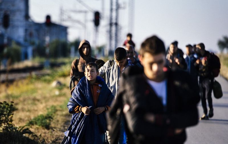 Migrants walk on a road near the southern Serbian town of Presevo, near the border with Macedonia, on July 15, 2015. Migrants cross Serbia to join other European countries, as it has land borders with three EU countries - Romania, Hungary and Croatia. The estimated number of people crossing the Serbia-Hungary border has increased more than 25-fold, rising from 2,370 to 60,602 according to an Amnesty International report.  /
