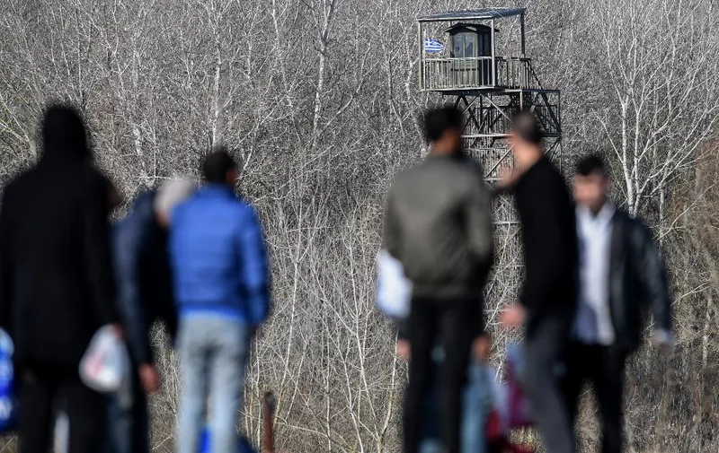 Migrants look towards to Greek military post guard tower, near the Evros river, near Edirne, in northwestern Turkey, as they waits take a boat to attempt to enter Greece by crossing the river on March 3, 2020. - Turkey's Interior Minister Suleyman Soylu says nearly 50,000 migrants have left Turkey for Europe via the northwestern province of Edirne, bordering Greece. Greece goes onto a state of "maximum" alert to protect its borders and was suspending asylum applications by those who entered the country illegally. (Photo by Ozan KOSE / AFP)