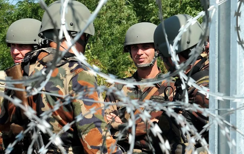 Hungarian border police and military personel stand guard next to a barb-wire fence, near the Serbia-Hungary border near the Serbian town of Horgos on September 14, 2015. Hungary has effectively stopped registering thousands of migrants crossing the border from Serbia and is transporting them straight to the Austrian frontier, the UN refugee agency said September 14. AFP PHOTO / ELVIS BARUKCIC