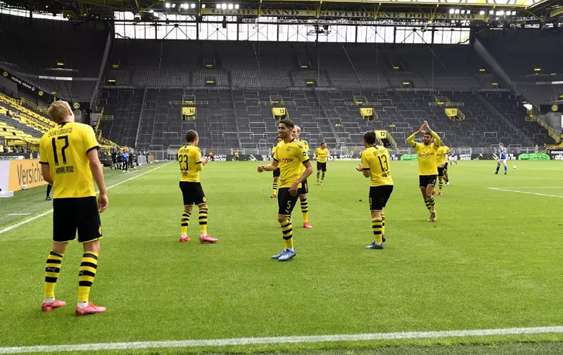 Dortmund's Norwegian forward Erling Braut Haaland (L) celebrates with team players after scoring the opening goal during the German first division Bundesliga football match BVB Borussia Dortmund v Schalke 04 on May 16, 2020 in Dortmund, western Germany as the season resumed following a two-month absence due to the novel coronavirus COVID-19 pandemic. (Photo by Martin Meissner / POOL / AFP) / DFL REGULATIONS PROHIBIT ANY USE OF PHOTOGRAPHS AS IMAGE SEQUENCES AND/OR QUASI-VIDEO