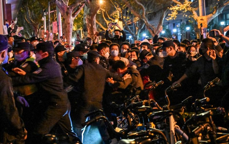 Police and guards arrest a man during some clashes in Shanghai on November 27, 2022, where protests against China's zero-Covid policy took place the night before following a deadly fire in Urumqi, the capital of the Xinjiang region. (Photo by HECTOR RETAMAL / AFP)