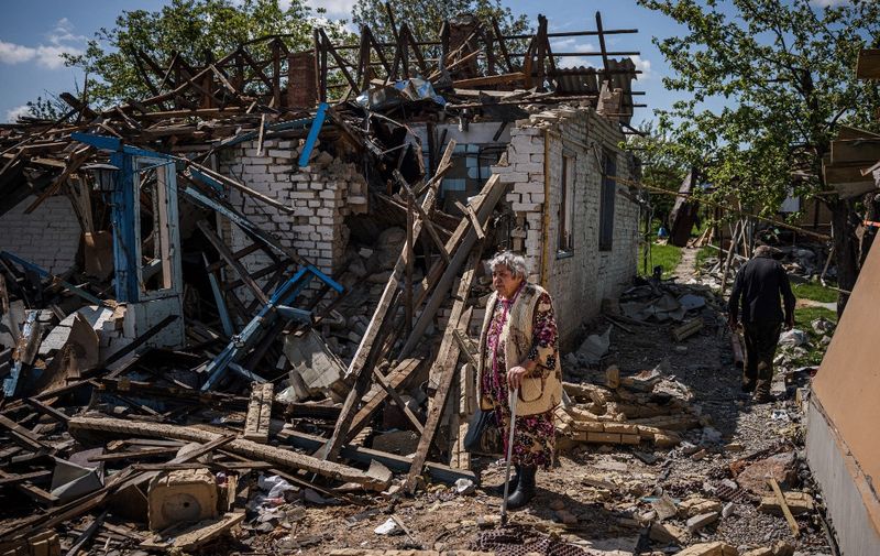 A couple brings their luggage out of their destroyed house in the village of Vilkhivka, near the eastern city of Kharkiv, on May 14, 2022, on the 80th day of the Russian invasion of Ukraine. - Dozens of houses in Vilkhivka, a village of about 2,000 inhabitants, were gutted by shells, explosions or fires. Debris litter the streets including bullet casings, and remains of ammunition. (Photo by Dimitar DILKOFF / AFP)