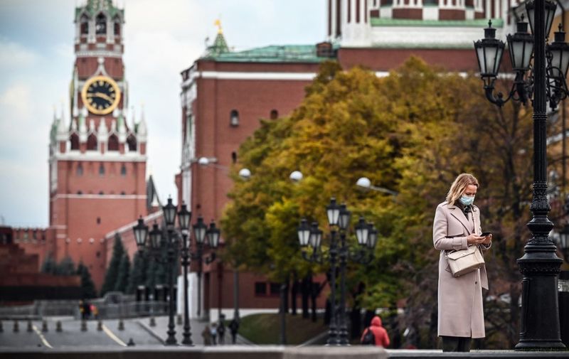 A woman wearing a protective mask stands at thge edge of the Red Square in downtown Moscow on November 10, 2020, amid the ongoing coronavirus disease pandemic. - Russia has confirmed 20,977 new Covid-19 daily cases including 5,902 in Moscow. (Photo by Alexander NEMENOV / AFP)
