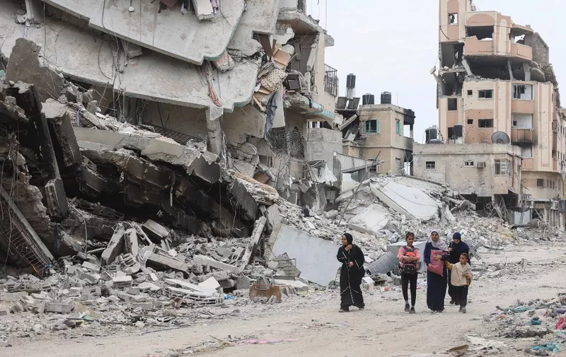 Palestinian women and children walk past the ruins of buildings destroyed by earlier Israeli bombardment in Gaza City on April 8, 2024, amid the ongoing conflict between Israel and the Palestinian Hamas militant group. (Photo by AFP)
