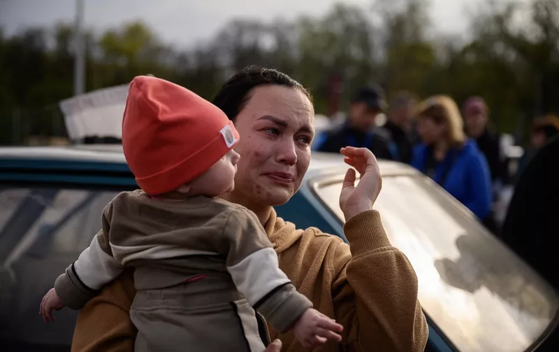 A woman reacts as she holds a child after arriving from a Russian-occupied territory at a registration and processing area for internally displaced people in Zaporizhzhia, in Ukraine, on May 2, 2022. (Photo by Ed JONES / AFP)