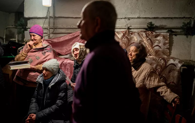Worshippers pray during an Orthodox Christmas mass in a basement shelter in Chasiv Yar, Eastern Ukraine, on January 7, 2023, amid the Russian invasion of Ukraine. - As artillery boomed outside and fighter jets flew overhead, Orthodox Christians in a battered east Ukraine town held a Christmas service in a basement shelter on January 7, vowing not to let war ruin the holiday. (Photo by Dimitar DILKOFF / AFP)