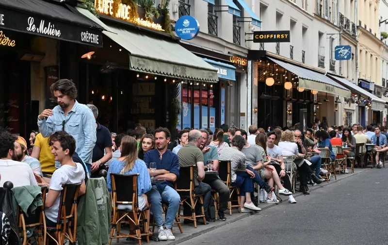 People eat and have drinks at a cafe terrace in the rue de Buci in Paris on June 2, 2020, as cafes and restaurants reopen in France with the easing of lockdown mesures taken to curb the spread of the COVID-19 pandemic, caused by the novel coronavirus. - French cafes and restaurants reopened their doors on June 2 as the country took its latest step out of coronavirus lockdown, with clients seizing the chance to bask on sunny terraces after 10 weeks of closures to fight the outbreak. (Photo by BERTRAND GUAY / AFP)