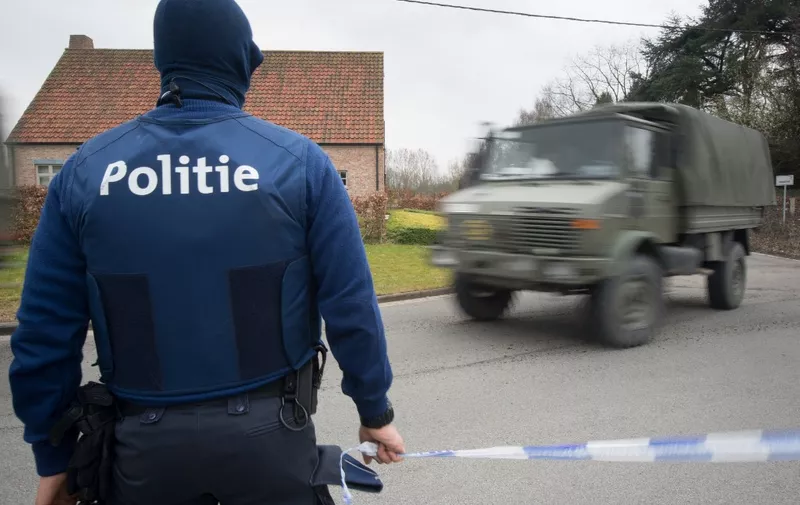 A Belgian police officer stands as a military vehicle drives near the closed hotel and restaurant Villa Marquette on March 31, 2016, in Courtrai, during an operation in connection with a foiled attack plot in France, whose main suspect was charged this week with membership of a terrorist organisation. - "A raid is under way in connection with the (Reda) Kriket case. It is taking place at Marke, in the town of Courtrai" in northwestern Belgium, Eric Van Der Sypt, a spokesman for the federal prosecutor's office, told AFP. French national Reda Kriket was arrested near Paris last week and at his apartment police found a cache of assault rifles, handguns and TATP, the highly volatile homemade explosive favoured by Islamic State (IS) jihadists. (Photo by BENOIT DOPPAGNE / Belga / AFP) / Belgium OUT