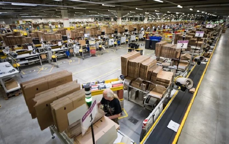 Employees of American electronic commerce company Amazon prepare items for dispatch in Bad Hersfeld, central Germany on December 7, 2017.
To cope with the high-turnover Christmas business, Amazon has hired 13,000 temporary employees. / AFP PHOTO / dpa / Swen Pförtner / Germany OUT