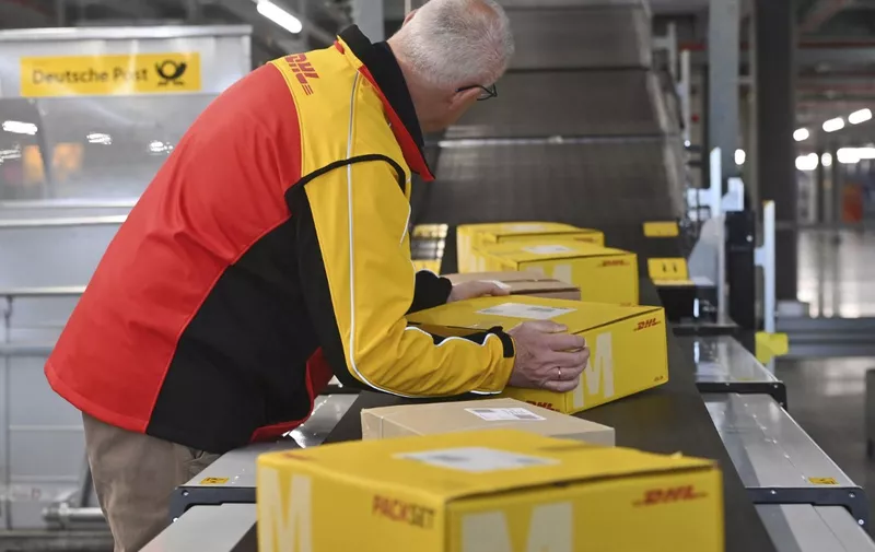 Deutsche Post DHL puts Germany's largest parcel location into operation on March 20th, 2023. Processing of up to 72,000 parcels per hour in the Aschheim II parcel center near Munich. Worker puts packages on a belt, conveyor belt. ? (Photo by Frank Hoermann / SVEN SIMON / SVEN SIMON / dpa Picture-Alliance via AFP)