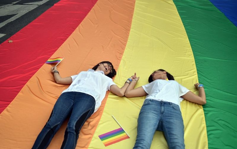 Participants of the Belgrade Gay Pride parade lay on a giant rainbow flag on September 20, 2015. The participants of Belgrade Gay Pride parade, held without incidents and under tight security, urged  for European solidarity with migrants traveling across Balkans towards European Union. The march, the second in a row since the event was marred by violence in 2010, was held without incidents amid tight security as thousands of riot police officers were deployed in the city center.   AFP PHOTO / ANDREJ ISAKOVIC