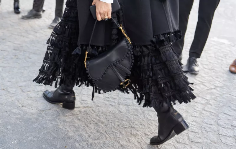 Detail of a black Dior bag with pompom trim, boots and tasseled skirt at the show.
Paris Fashion Week F/W 2023, Streetstyle, Paris, France - 10 Mar 2023,Image: 761919163, License: Rights-managed, Restrictions: , Model Release: no