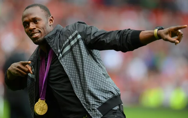 Manchester United supporter and Jamaican Olympic sprint champion Usain Bolt from Jamaica walks onto the pitch with his gold medals before the English Premier League football match between Manchester United and Fulham at Old Trafford in Manchester, north-west England on August 25, 2012. AFP PHOTO/ANDREW YATES

RESTRICTED TO EDITORIAL USE. No use with unauthorized audio, video, data, fixture lists, club/league logos or “live” services. Online in-match use limited to 45 images, no video emulation. No use in betting, games or single club/league/player publications / AFP / ANDREW YATES