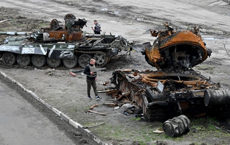 Residents look at a destroyed Russian tank on the outskirts of Buzova village, west of Kyiv, on April 10, 2020. -  (Photo by Sergei SUPINSKY / AFP)