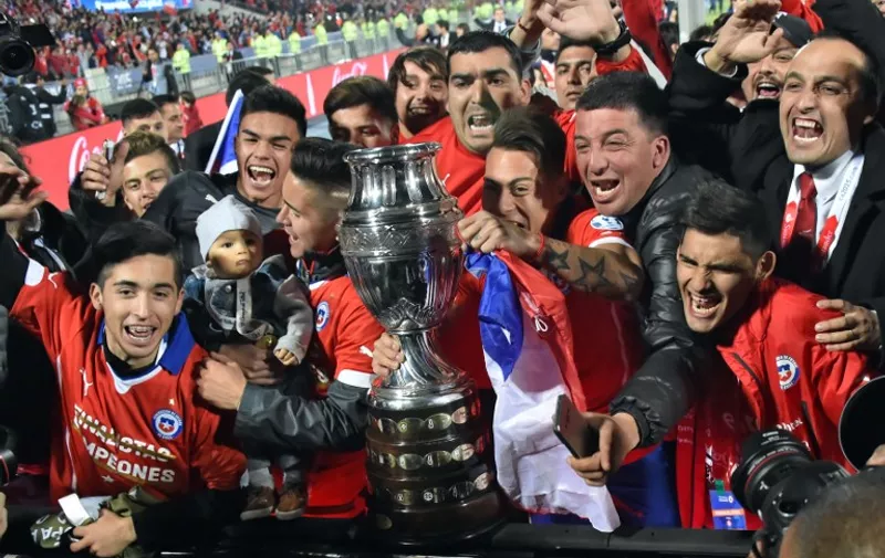Chile's forward Eduardo Vargas (C) holds the trophy and celebrates after winning the 2015 Copa America football championship final against Argentina, in Santiago, Chile, on July 4, 2015. Chile won 4-1 (0-0).    AFP PHOTO / NELSON ALMEIDA