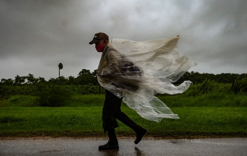 A man walks under the rain in Batabano, Mayabeque province, about 60 km south of Havana, on August 27, 2021, as Hurricane Ida passes through eastern Cuba. (Photo by Yamil LAGE / AFP)